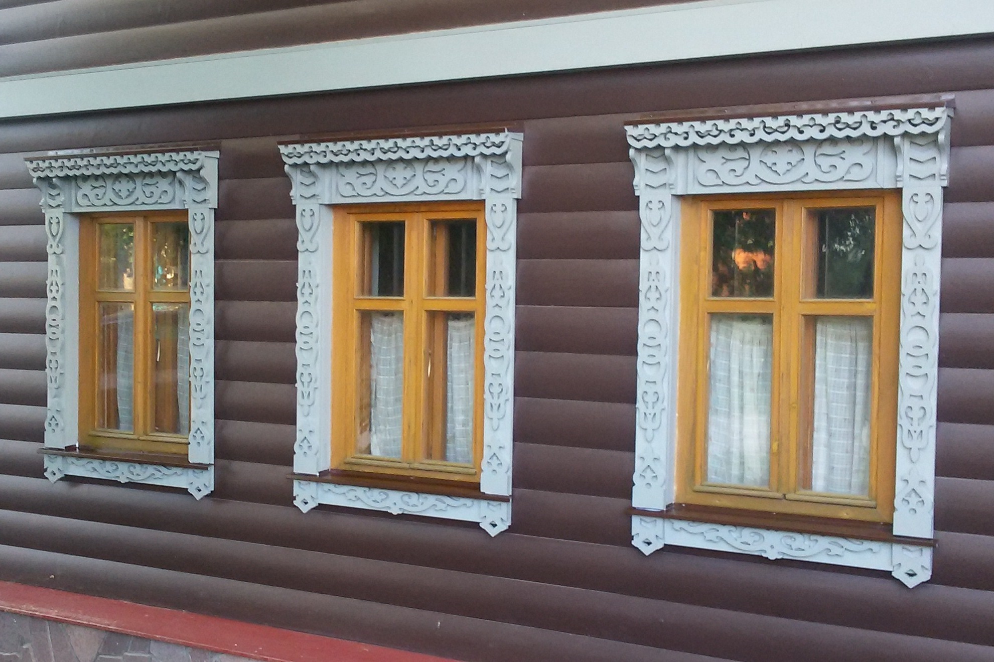 Фасад деревянного дома украшенный уникальными резными наличниками